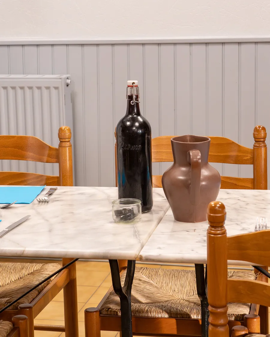 La table du soir dressée au gîte : carafe, bouteille et couverts sur le marbre